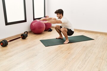 Wall Mural - Young hispanic man smiling confident training legs exercise at sport center