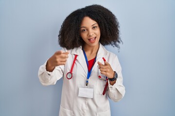 Wall Mural - Young african american woman wearing doctor uniform and stethoscope pointing fingers to camera with happy and funny face. good energy and vibes.