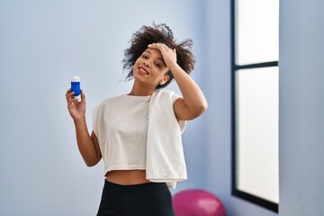 Sticker - Young african american woman wearing sportswear and towel holding deodorant stressed and frustrated with hand on head, surprised and angry face