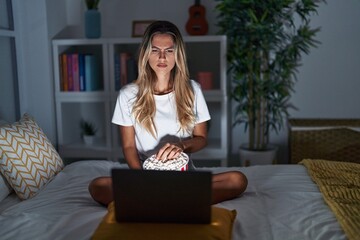 Canvas Print - Young blonde woman sitting on the bed at home watching a movie from laptop skeptic and nervous, frowning upset because of problem. negative person.