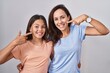 © Krakenimages.com - Young mother and daughter standing over white background smiling cheerful showing and pointing with fingers teeth and mouth. dental health concept.