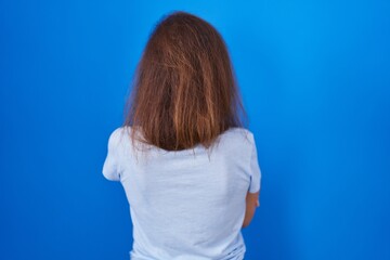 Poster - Brunette woman standing over blue background standing backwards looking away with crossed arms