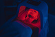© callisto - LED red light is treating the facial skin of a young woman.