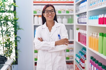 Wall Mural - Young beautiful hispanic woman pharmacist smiling confident standing with arms crossed gesture at pharmacy