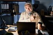 © Krakenimages.com - Middle age man with grey hair working at the office at night cheerful with a smile on face pointing with hand and finger up to the side with happy and natural expression