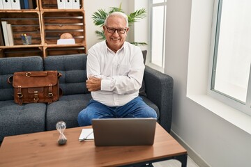 Canvas Print - Senior therapist with grey hair doing online session at consultation office happy face smiling with crossed arms looking at the camera. positive person.