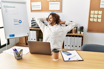 Wall Mural - Young hispanic businessman relaxed with hands on head sitting on the table at office.