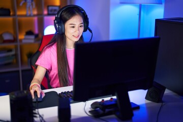 Poster - young chinese woman streamer playing video game using computer at gaming room