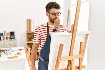 Canvas Print - Arab young man at art studio looking stressed and nervous with hands on mouth biting nails. anxiety problem.