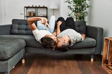 Poster - Two hispanic men couple kissing and lying on sofa at home