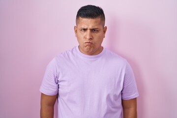 Poster - Young hispanic man standing over pink background skeptic and nervous, frowning upset because of problem. negative person.