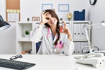 Poster - Young doctor woman holding electronic cigarette at medical clinic smiling happy doing ok sign with hand on eye looking through fingers