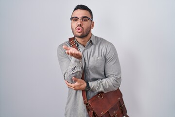 Canvas Print - Young hispanic man wearing suitcase looking at the camera blowing a kiss with hand on air being lovely and sexy. love expression.