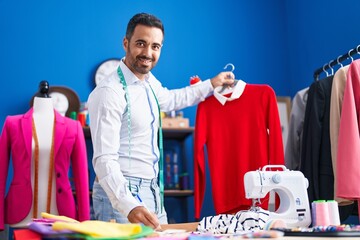 Sticker - Young hispanic man tailor holding t shirt write on paper at sewing studio