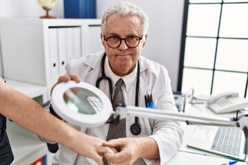 Poster - Middle age grey-haired man wearing dermatologist uniform using loupe at dermatology clinic