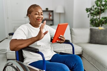 Wall Mural - Senior african american woman having video call sitting on wheelchair at home