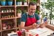 © Krakenimages.com - Middle age man florist using smartphone holding credit card at florist
