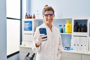 Poster - Young blonde woman wearing scientist uniform talking on the smartphone at laboratory