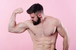 © Teodor Lazarev - Handsome bodybuilder flexing his bicep muscle, showing off a power pose, studio image on pink background