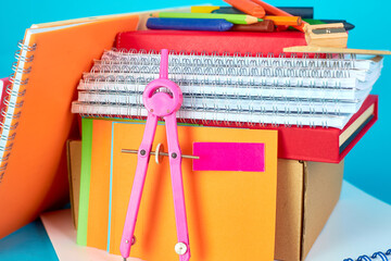Bright pink compass, geometry or architecture tool, laid on the notebook with pencils and other supplies