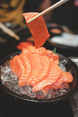 Wall Mural - Hands use chopsticks to hold the salmon sashimi. Japanese traditional food or with low calories.