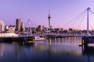 Wall Mural - Auckland, New Zealand September 20 2021: The sun sets over the Viaduct marina and Auckland business district skyscrapers in New Zealand largest city