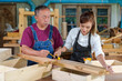 © ND STOCK - A tutor with a Female carpenter student in a workshop studying for an apprenticeship at a college using a tape measure.