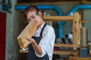 portrait of beautiful asian woman carpenter dealing with handicraft, woman has own business connected with making wooden furniture in workshop