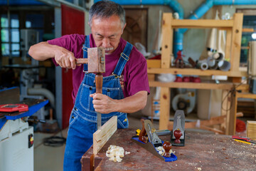 Wall Mural - carpenter hands working with a chisel and hammer on wooden workbench