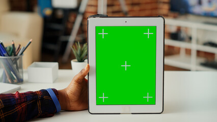 Young woman vertically holding device with green screen, analyzing isolated mockup template and blank copy space on digital tablet. Using chroma key display on wireless gadget. Close up.