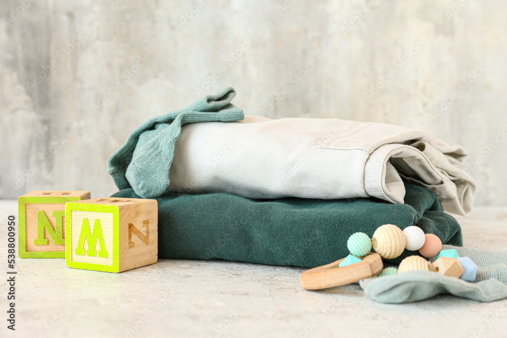 Children's clothes, wooden cubes and rattle on light background