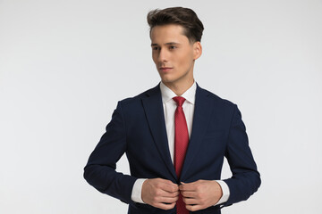 young businessman with red tie buttoning navy blue suit