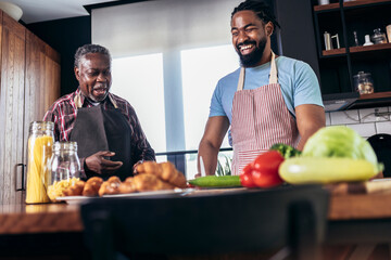 Adult son with his senior father cooking in the kitchen.