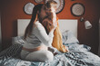© natalialeb - Middle-aged pregnant mother and toddler baby together on bed in bedroom in real interior.