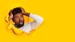 © Prostock-studio - Shocked millennial african american guy holding with hands his head and looking through hole in yellow paper