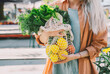 © Westend61 - Customer holding leafy vegetables and lemons in mesh bag at local market