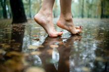 Woman Walking With Bare Feet Through Puddles In Park