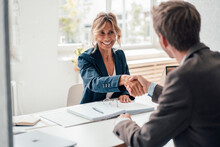 Happy Businesswoman Doing Handshake With Man At Office