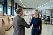 © Westend61 - Happy businesswoman handshaking with colleague at warehouse