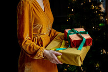 Woman With Yellow Dress Holding Christmas Gifts At Home