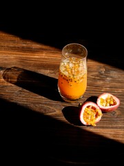 Canvas Print - Vertical shot of a passion fruits smoothie on the wooden table in a sunlight