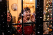 © Kawee - Adorable child look through the window and admiring first snow flakes.