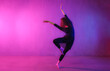 © Halfpoint - Modern dance girl dancer dancing in neon light doing gymnastic exercises in studio, copy space.