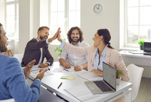 Excited millennial diverse employees give high five celebrate shared business success at office meeting. Overjoyed young businesspeople involved in teambuilding activity, motivated for win victory.