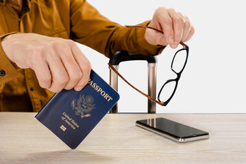 Wall Mural - Traveling young man handing USA passport while waiting for boarding, on a light gray studio background