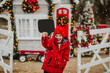 Cute young boy in red winter jacket holds empty name plate and posing on Christmas farm