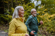 © Halfpoint - Happy senior couple hiking in autumn forest.