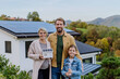 Happy family holding paper model of house with solar panels.Alternative energy, saving resources and sustainable lifestyle concept.