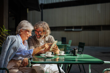 Wall Mural - Elderly couple with smartphone in outdoors cafe.