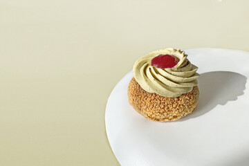 Choux pastry on a plate with whipped pistachio cream and currant confiture on a colored background isolated